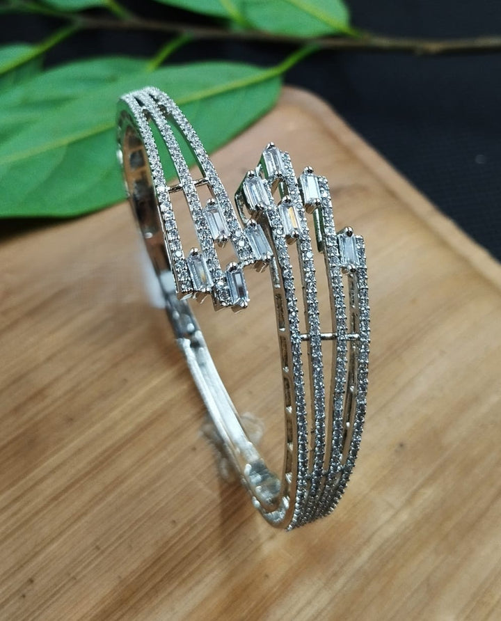 Silver bracelet with gemstones on a wooden surface with green leaves in the background