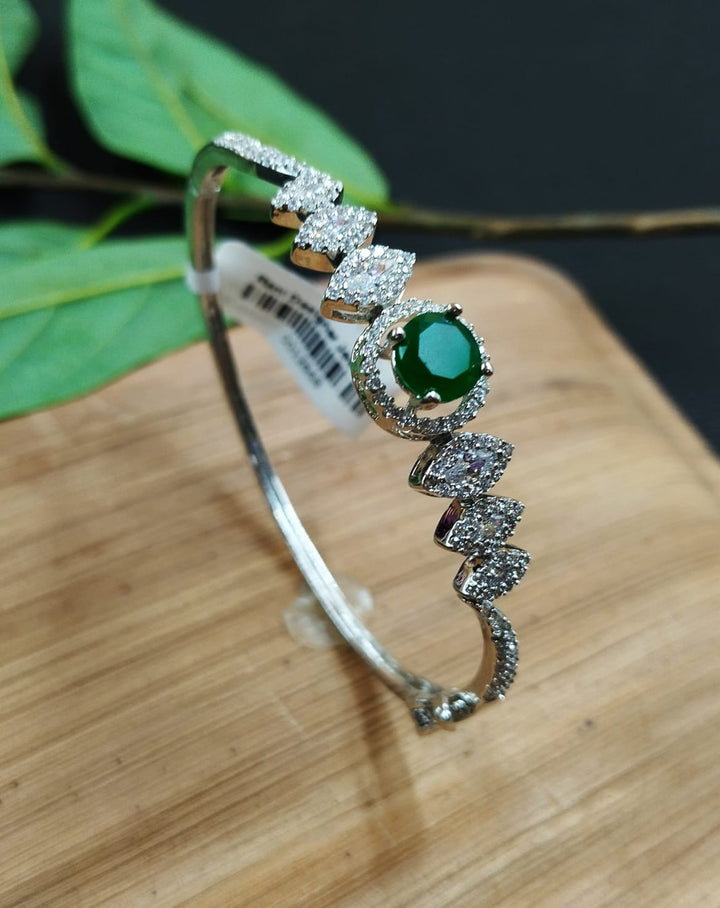 Silver bracelet with green gemstone on a wooden surface