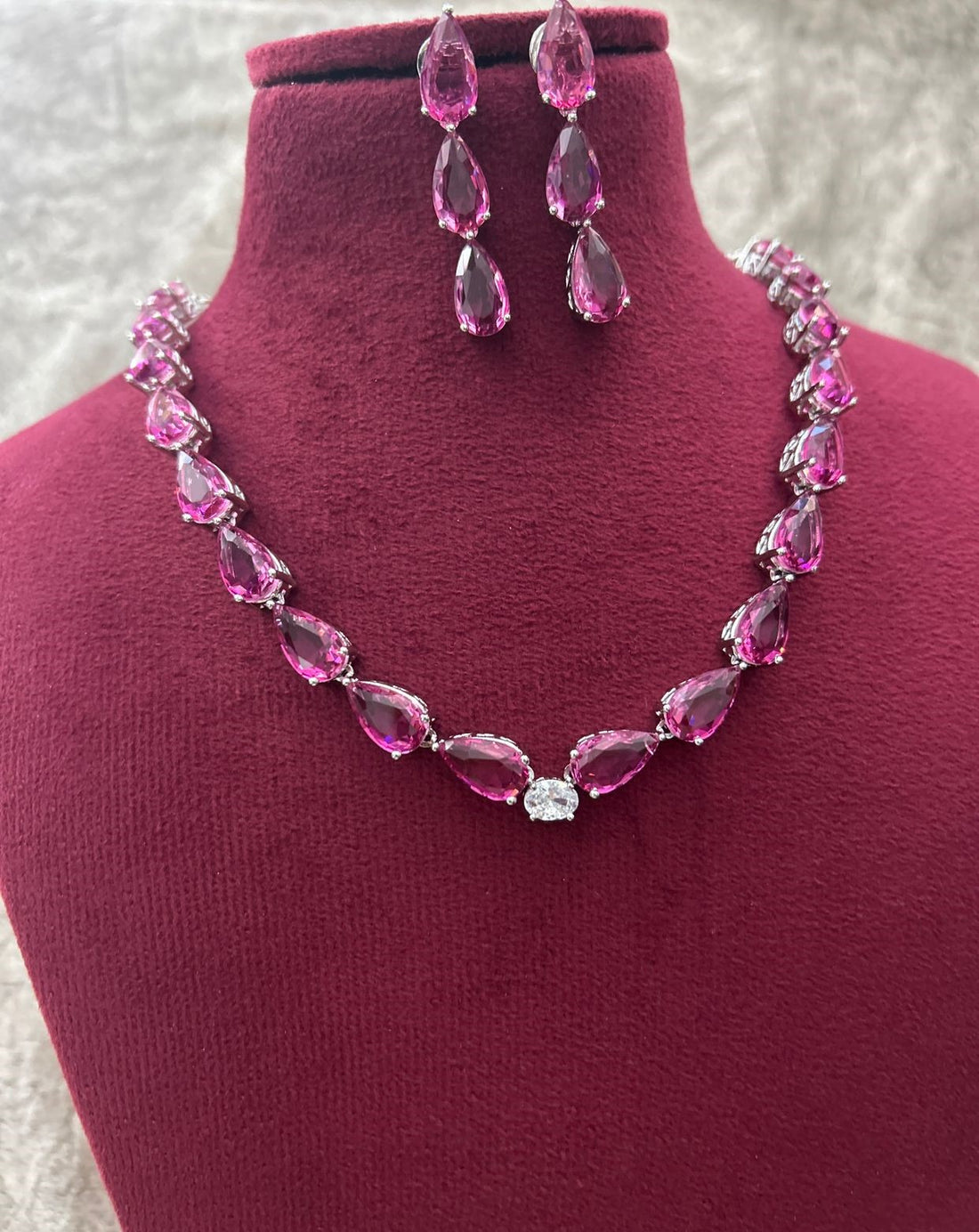 Pink crystal necklace and earrings set on a mannequin bust.