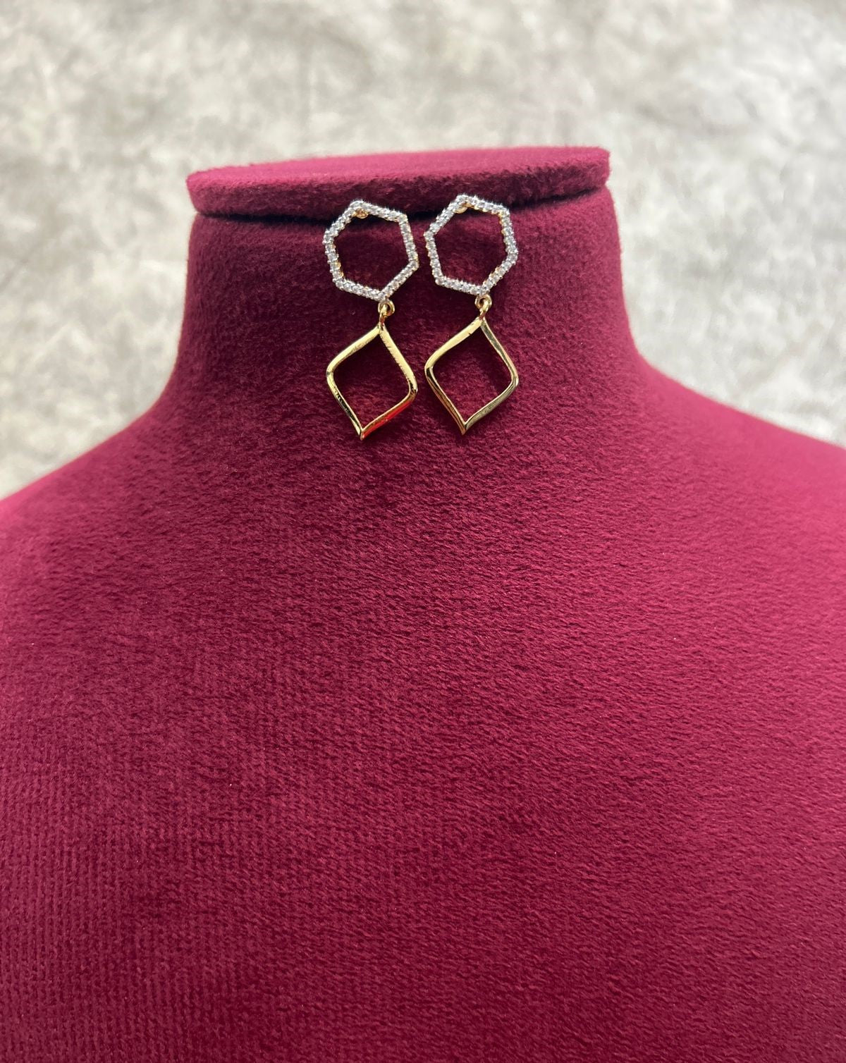 Gold and silver hoop earrings on a mannequin bust with a textured background