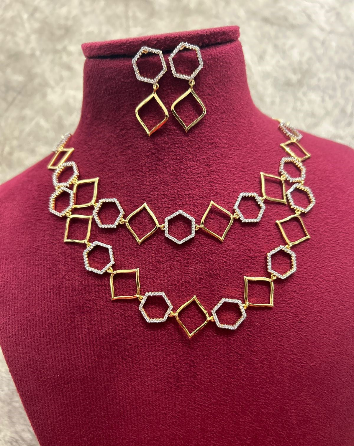 Gold and silver geometric necklace and earrings on a mannequin bust.