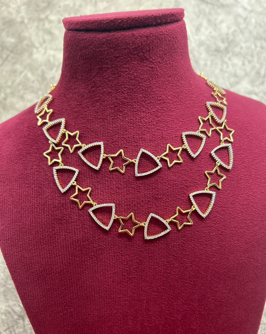 Necklace with star and triangle designs on a mannequin bust.