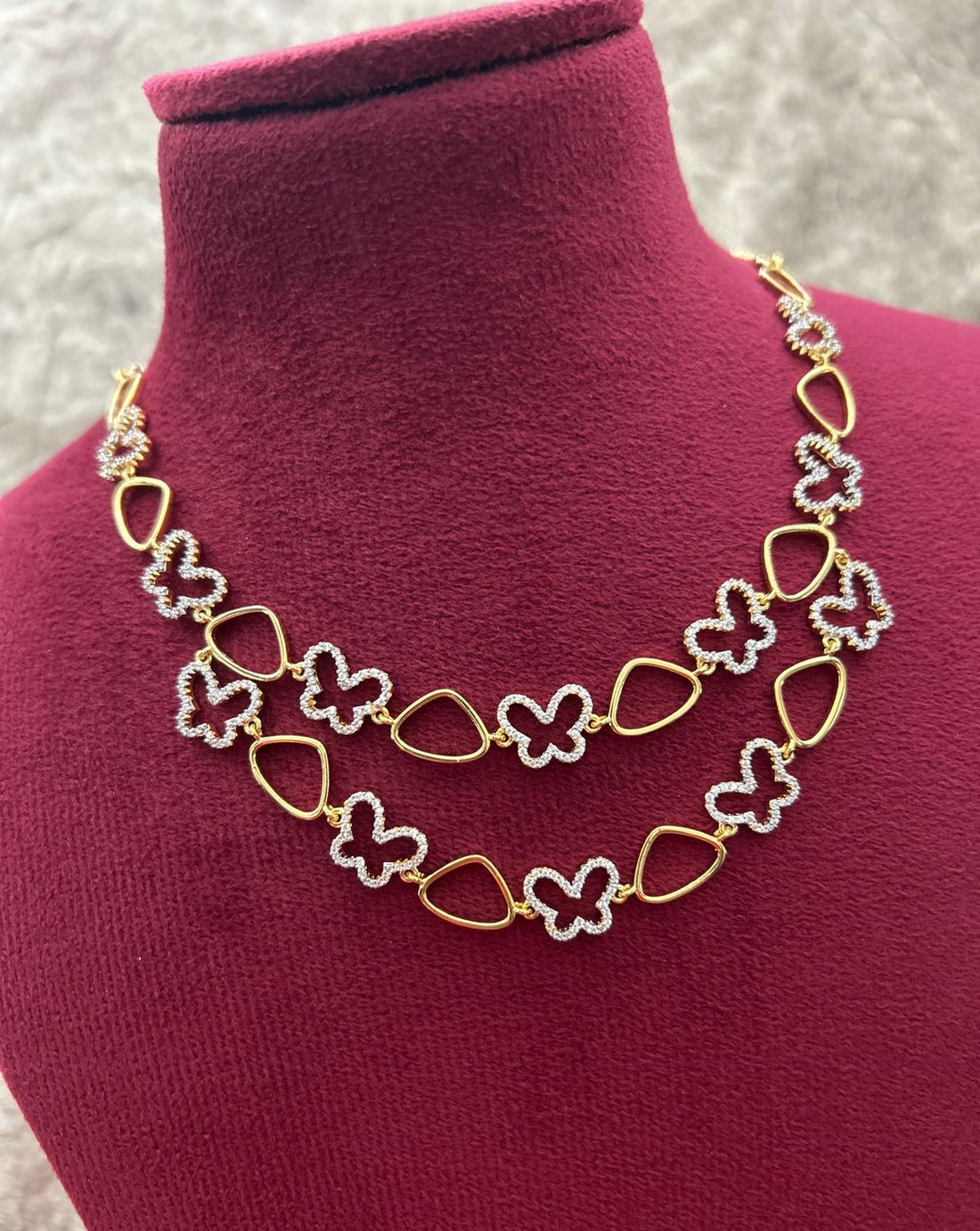 Gold and silver butterfly necklace on a mannequin bust.