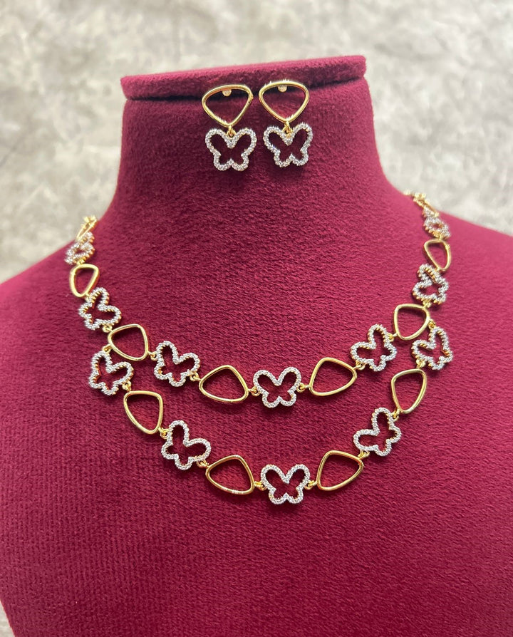 Butterfly-themed necklace and earrings set on a mannequin bust with a pink background