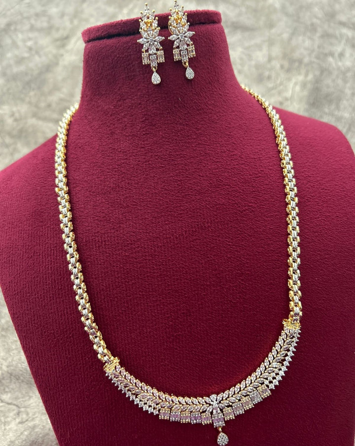 Gold and silver necklace with matching earrings on a mannequin bust.