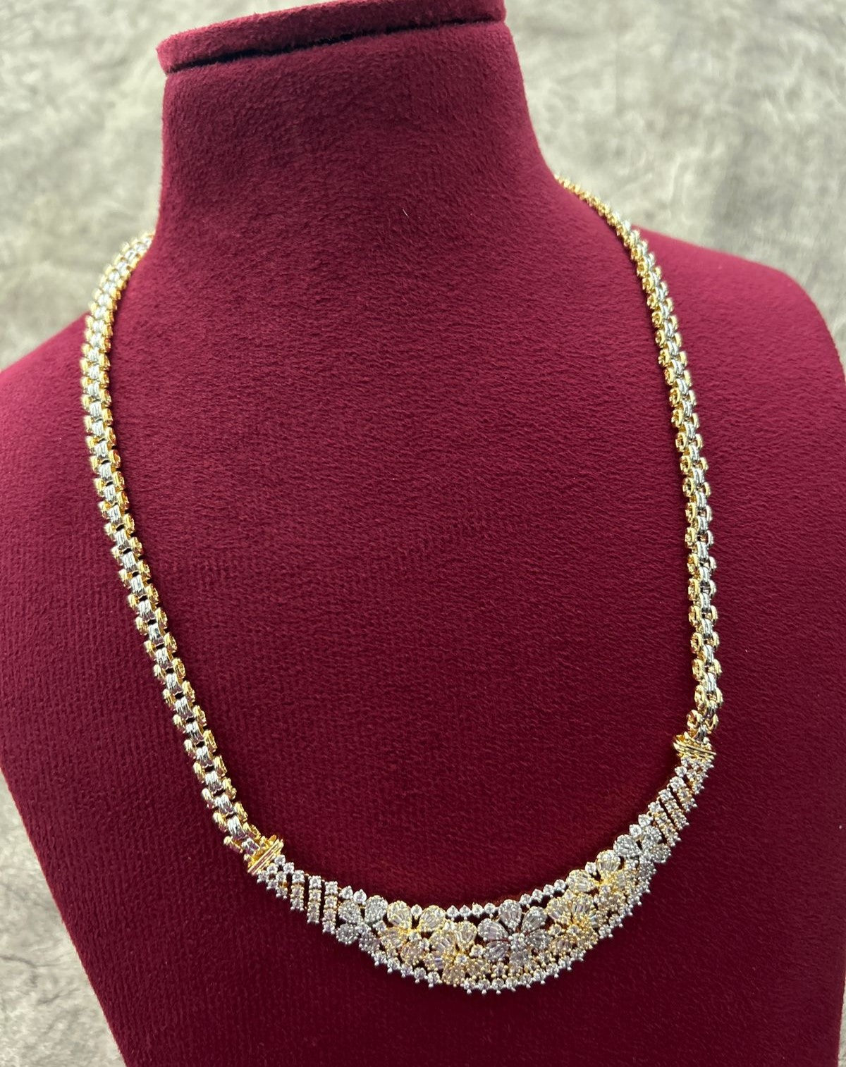 Gold and silver necklace on a mannequin bust with a gray background