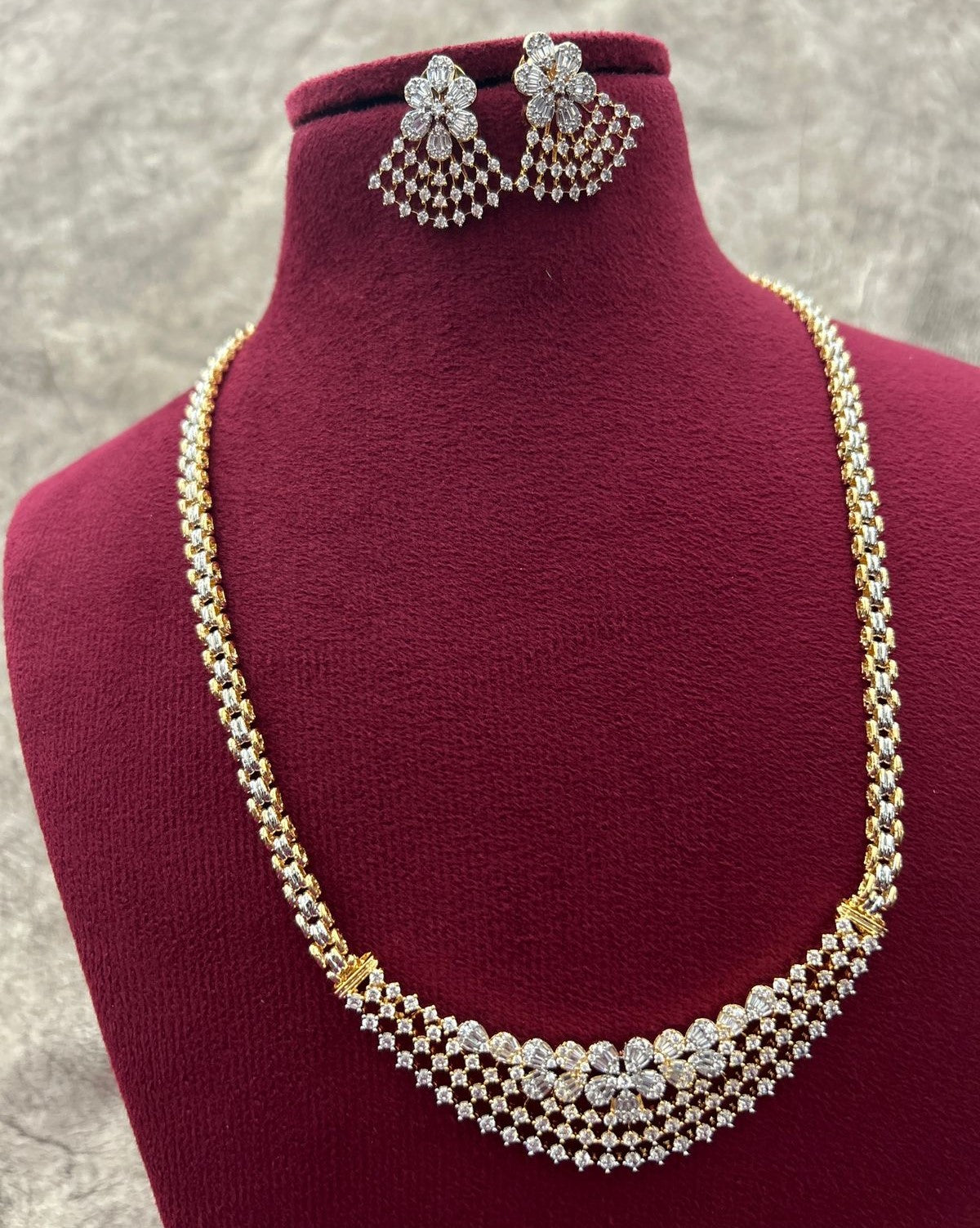Gold and diamond necklace with matching earrings on a mannequin bust.