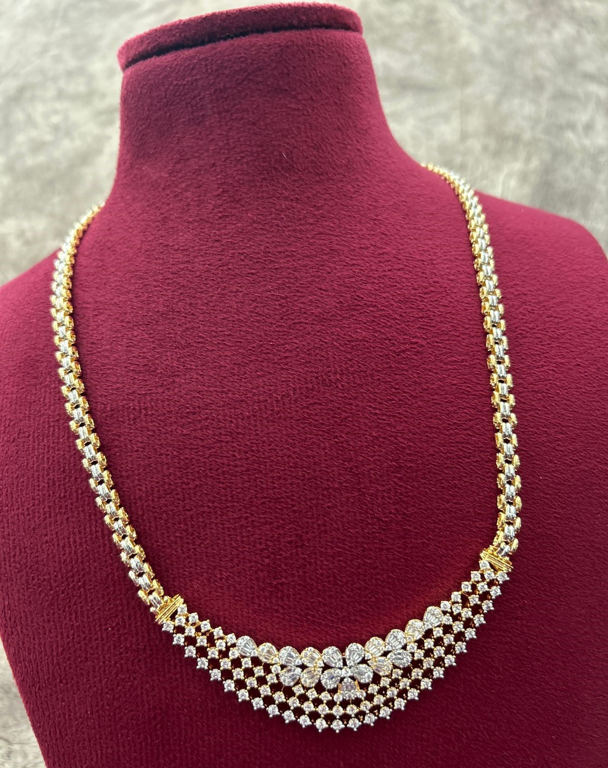 Gold and silver necklace on a mannequin bust with a gray background