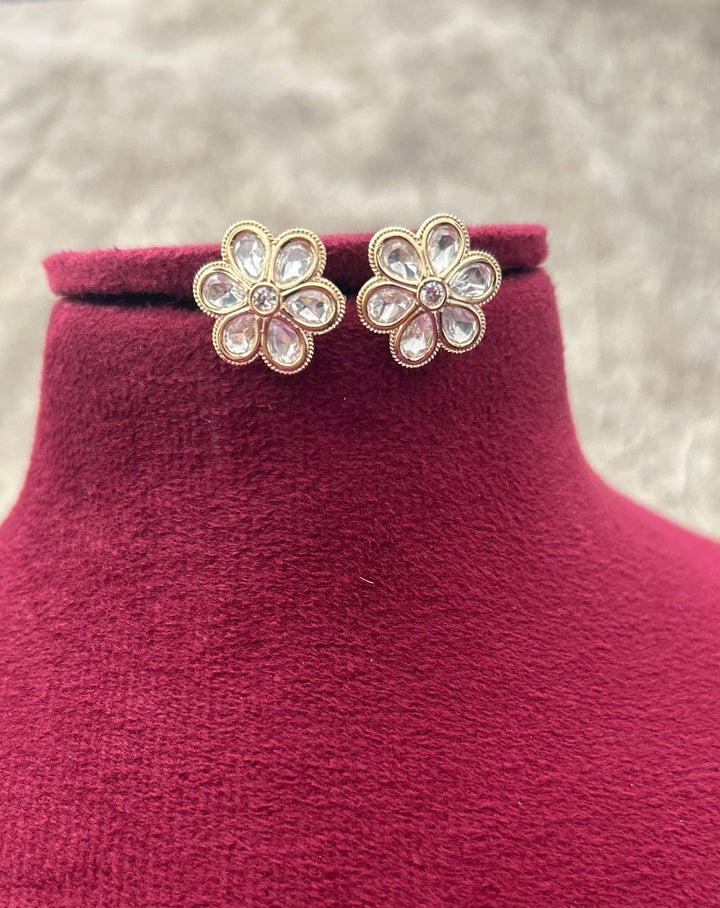 Flower-shaped earrings on a red velvet stand with a blurred background