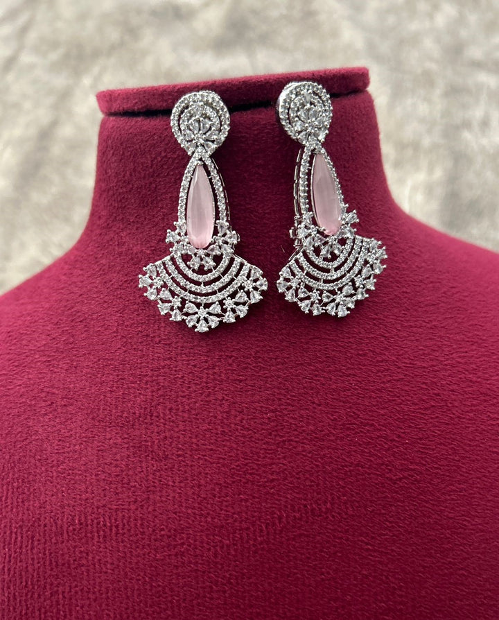 Ornate silver earrings on a mannequin with a textured background
