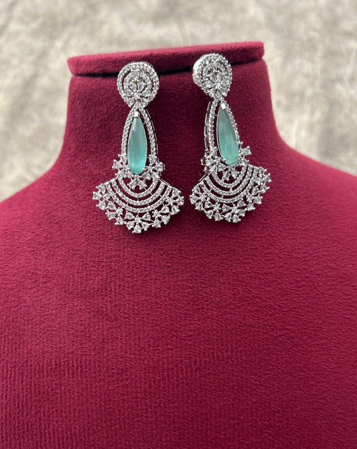 Pair of silver earrings with turquoise stones on a mannequin bust.