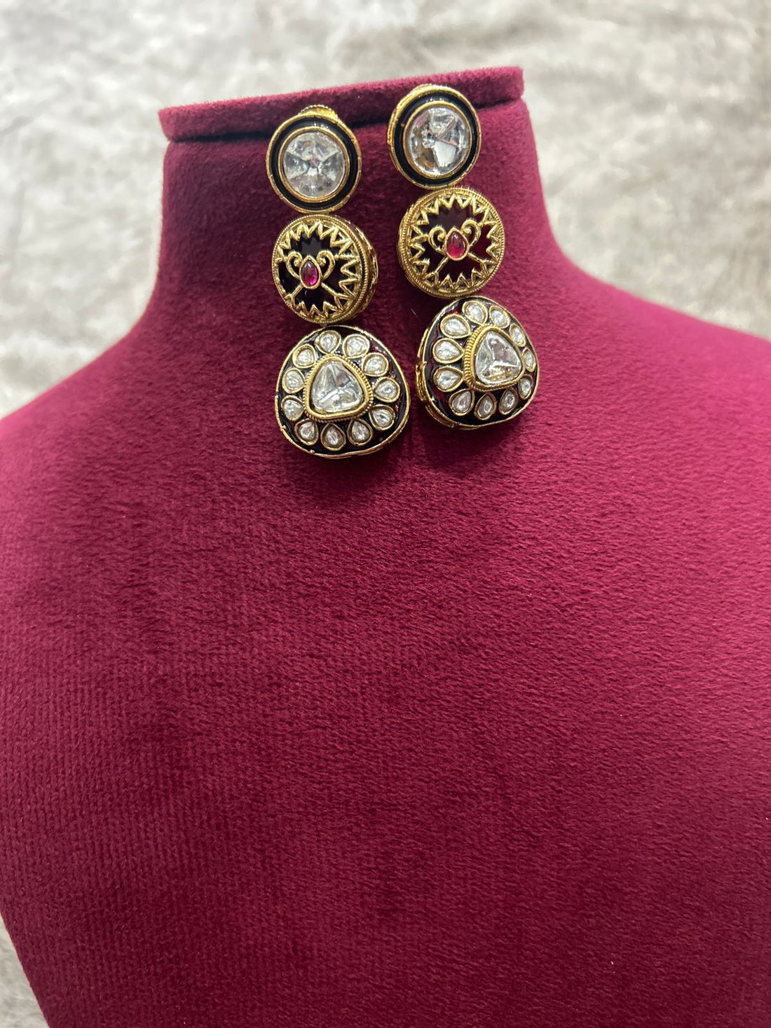 Gold and diamond earrings on a mannequin bust with a textured background