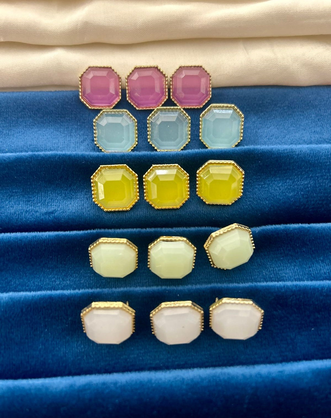 Set of colorful earring pairs on a blue fabric background