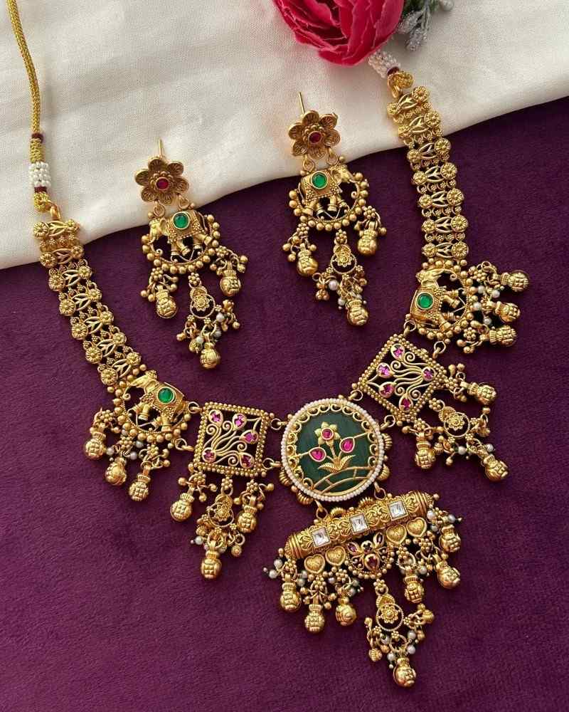 Gold necklace and earrings set on a purple fabric background