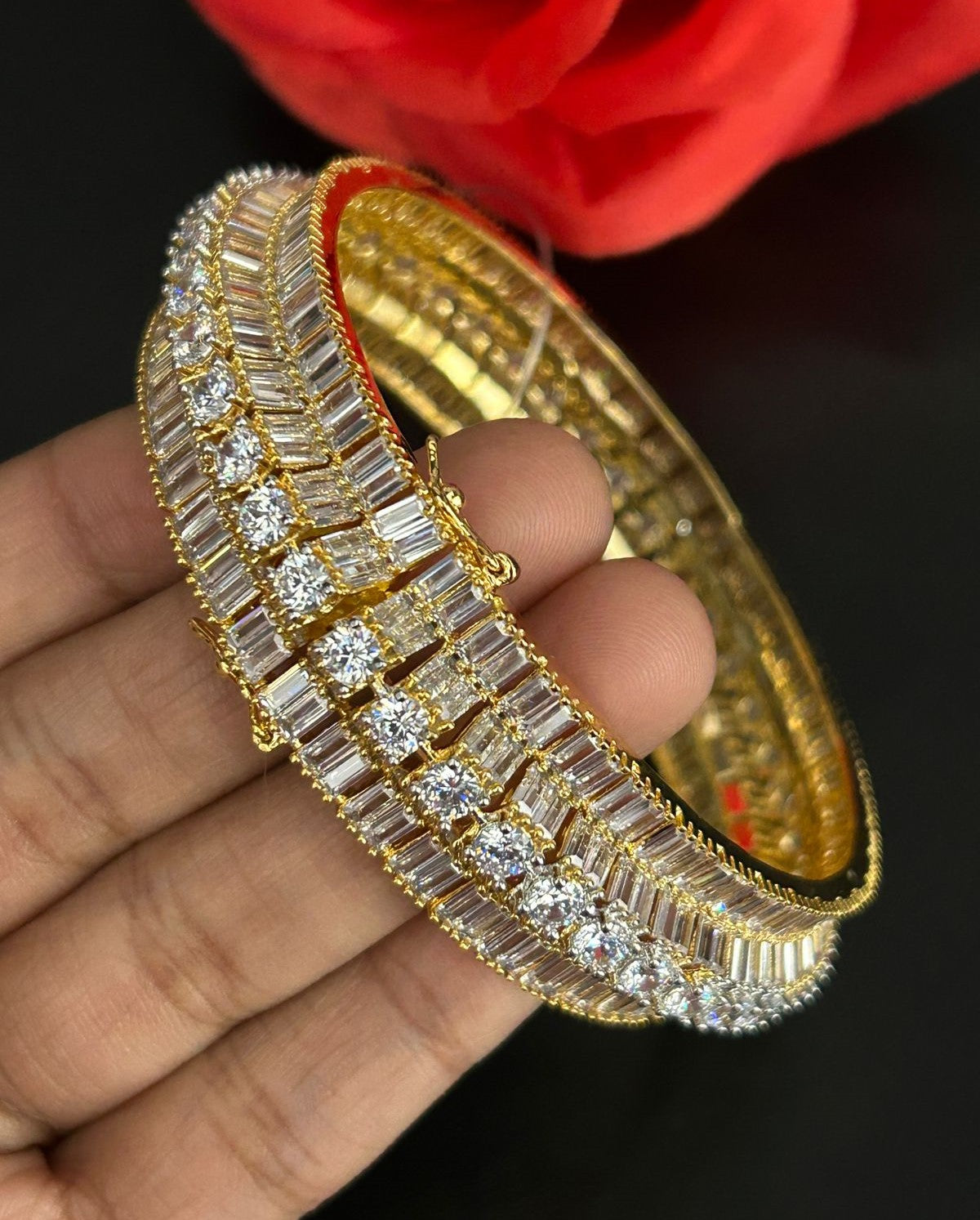 Gold bracelet with diamond accents held by a hand against a dark background