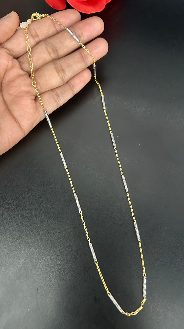 Gold chain held by a hand on a dark background