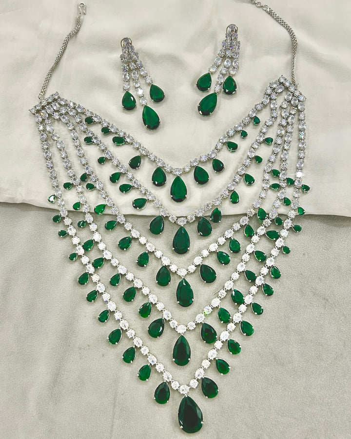 A silver-tone jewelry set featuring a multi-strand choker necklace, matching drop earrings, and a long pendant, 