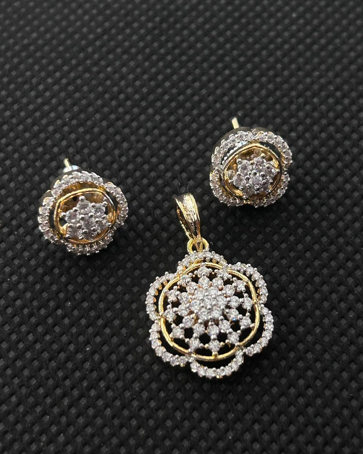 Gold and diamond jewelry set featuring a floral pendant and matching stud earrings, displayed on a textured black background.