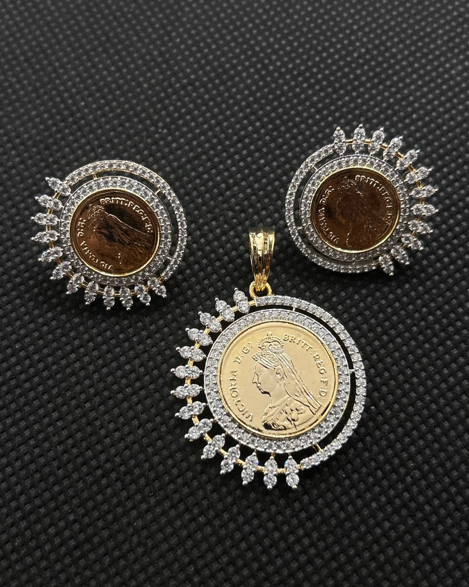 A jewelry set featuring a pendant and matching earrings, each with a gold-toned coin face surrounded by silver-toned halo settings and small clear stones, displayed on a textured black background.
