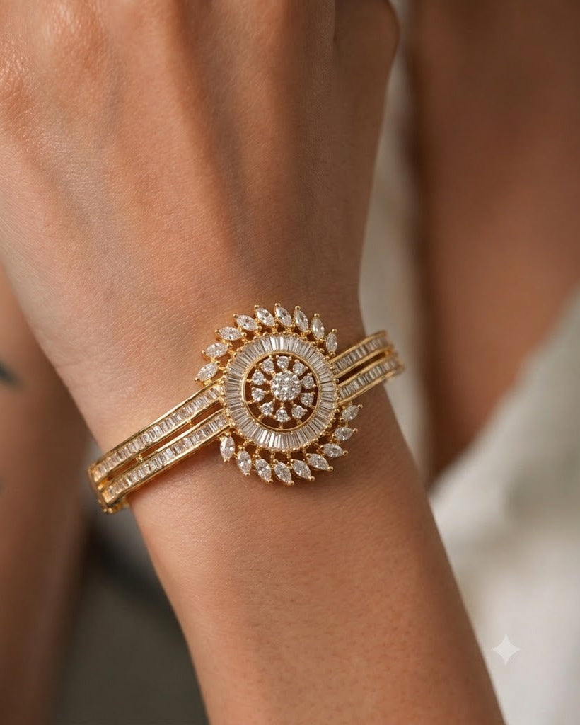 A close-up of a gold-toned bangle bracelet with a circular pavé center and diamond-encrusted bands, worn on a person's wrist.