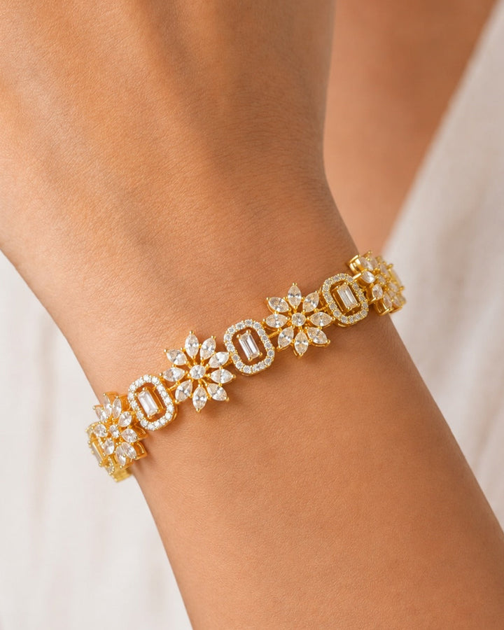 A close-up of a gold bracelet with diamond-encrusted floral and geometric motifs worn on a person's wrist.