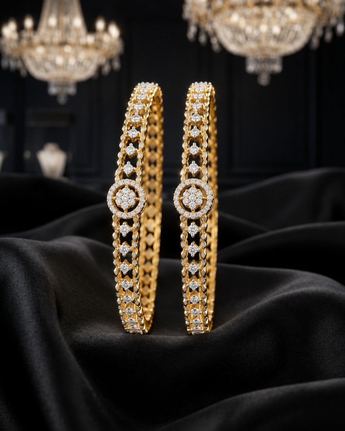Two gold bangles with intricate diamond-set patterns and circular medallion details, displayed on draped black fabric with blurred chandeliers in the background.