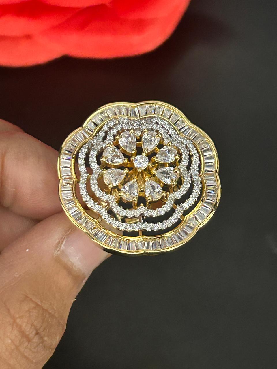 Gold and diamond ring held by a hand against a dark background