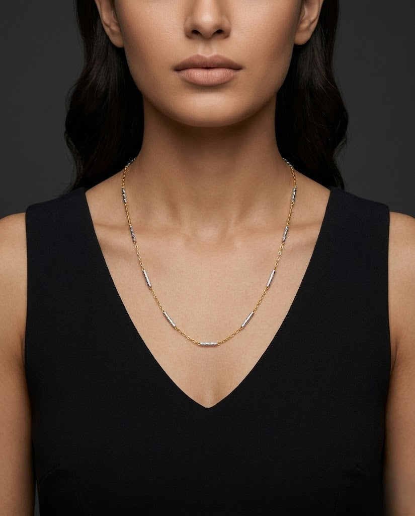 Woman wearing a delicate gold necklace against a dark background