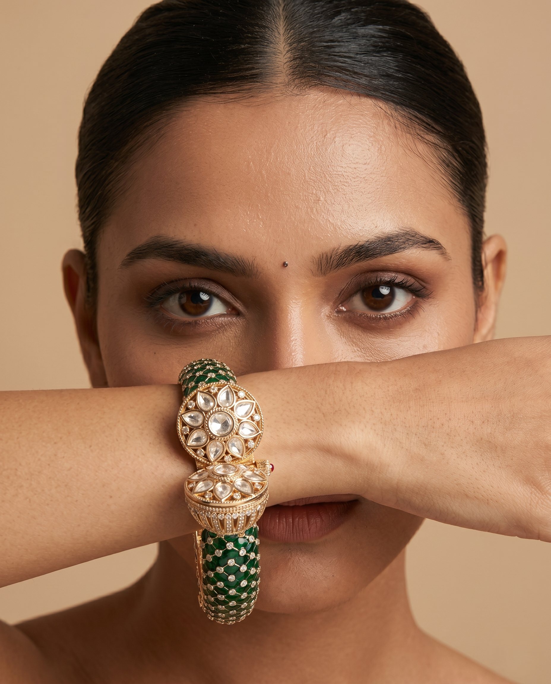 Woman wearing a gold and green bracelet on a beige background