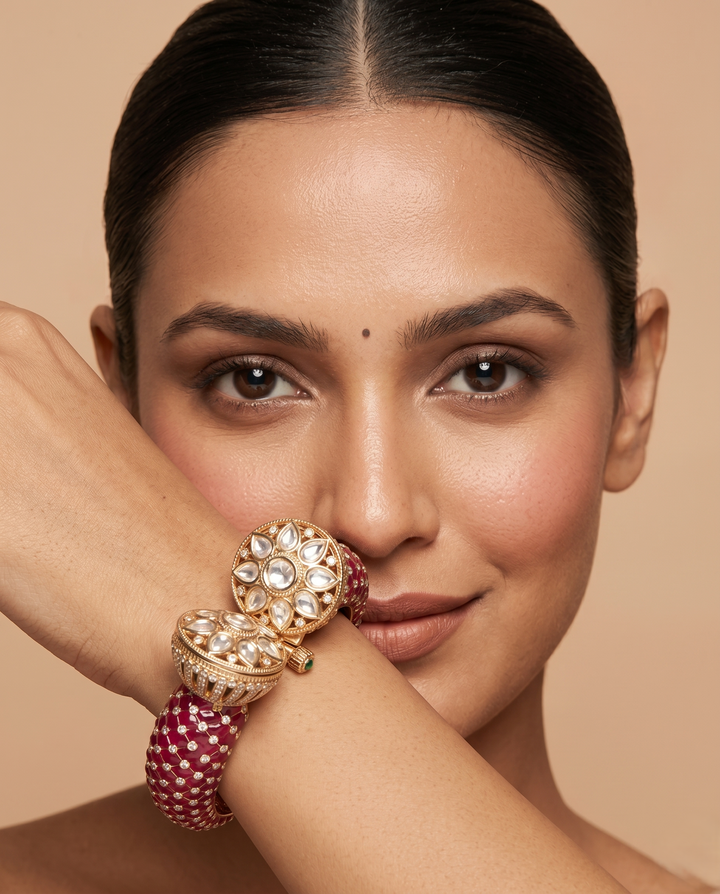 Woman wearing a gold and red bracelet on a beige background