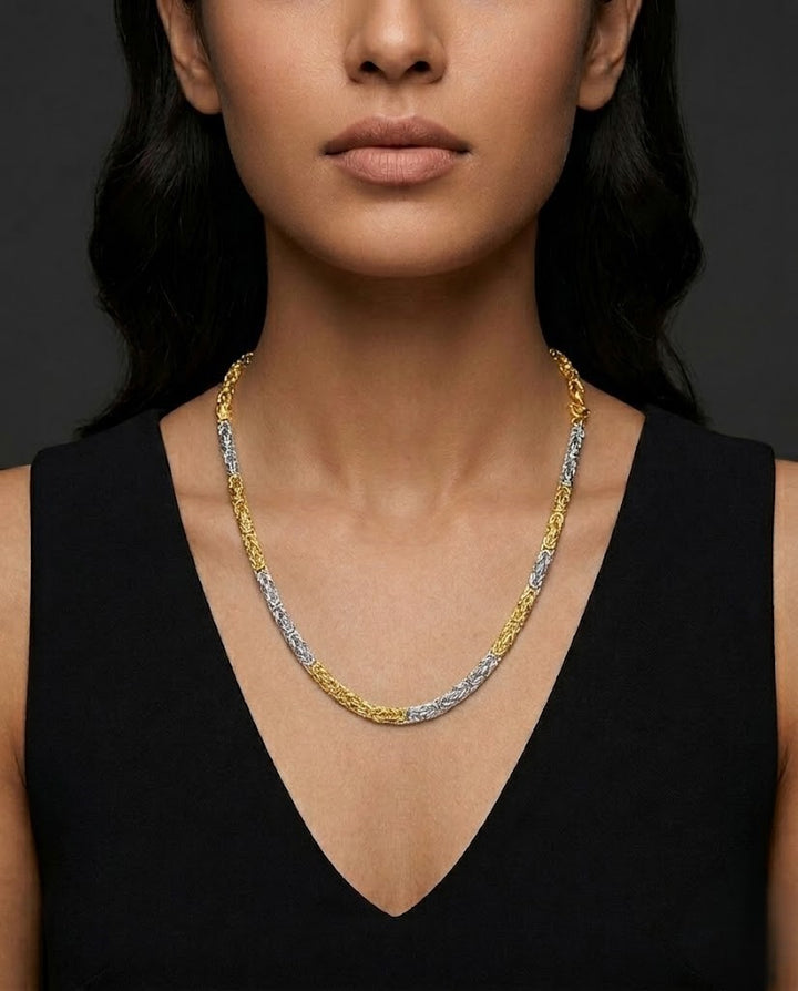 Woman wearing a gold and silver chain necklace against a dark background