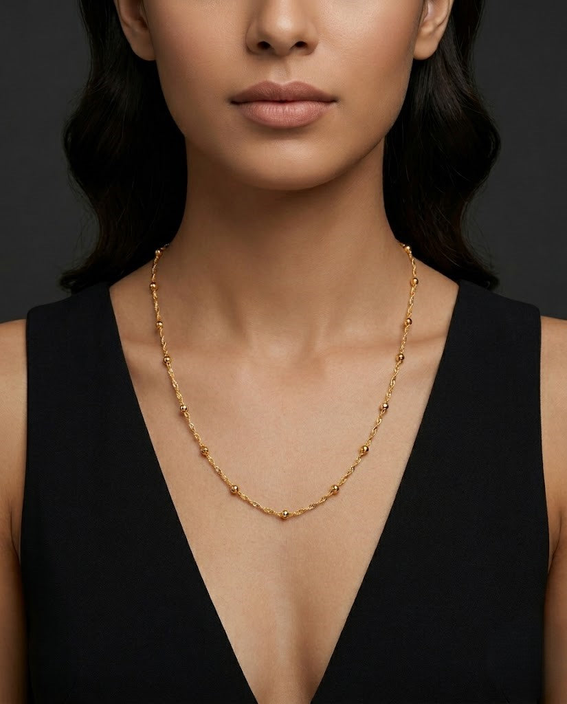 Woman wearing a gold necklace a dark background