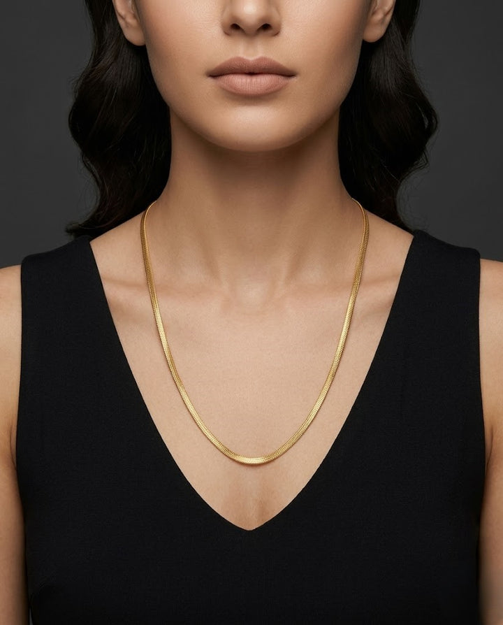 Woman wearing a gold necklace against a dark background