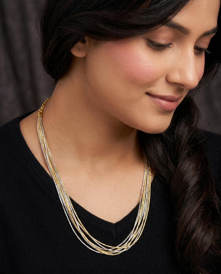 Woman wearing a gold necklace against a dark background