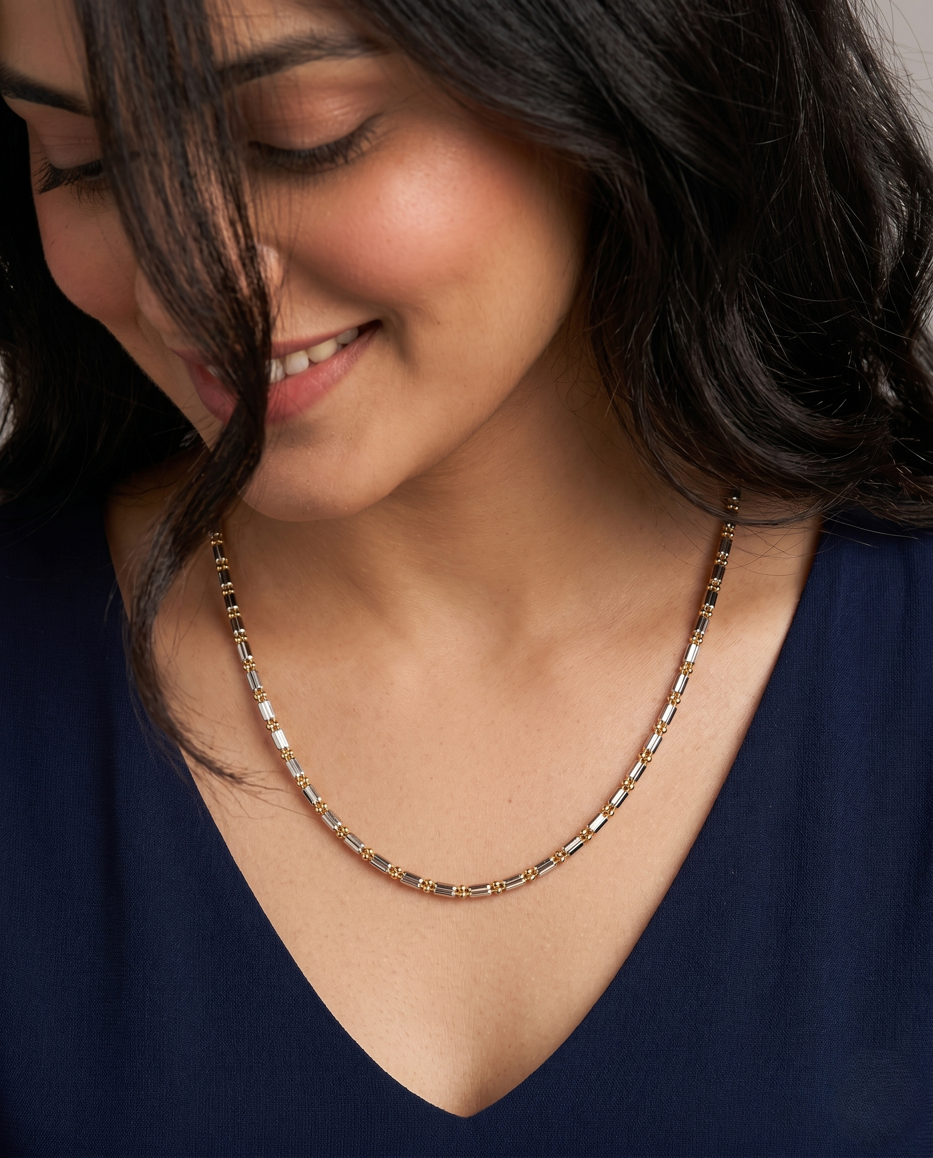 Woman wearing a gold necklace against a neutral background