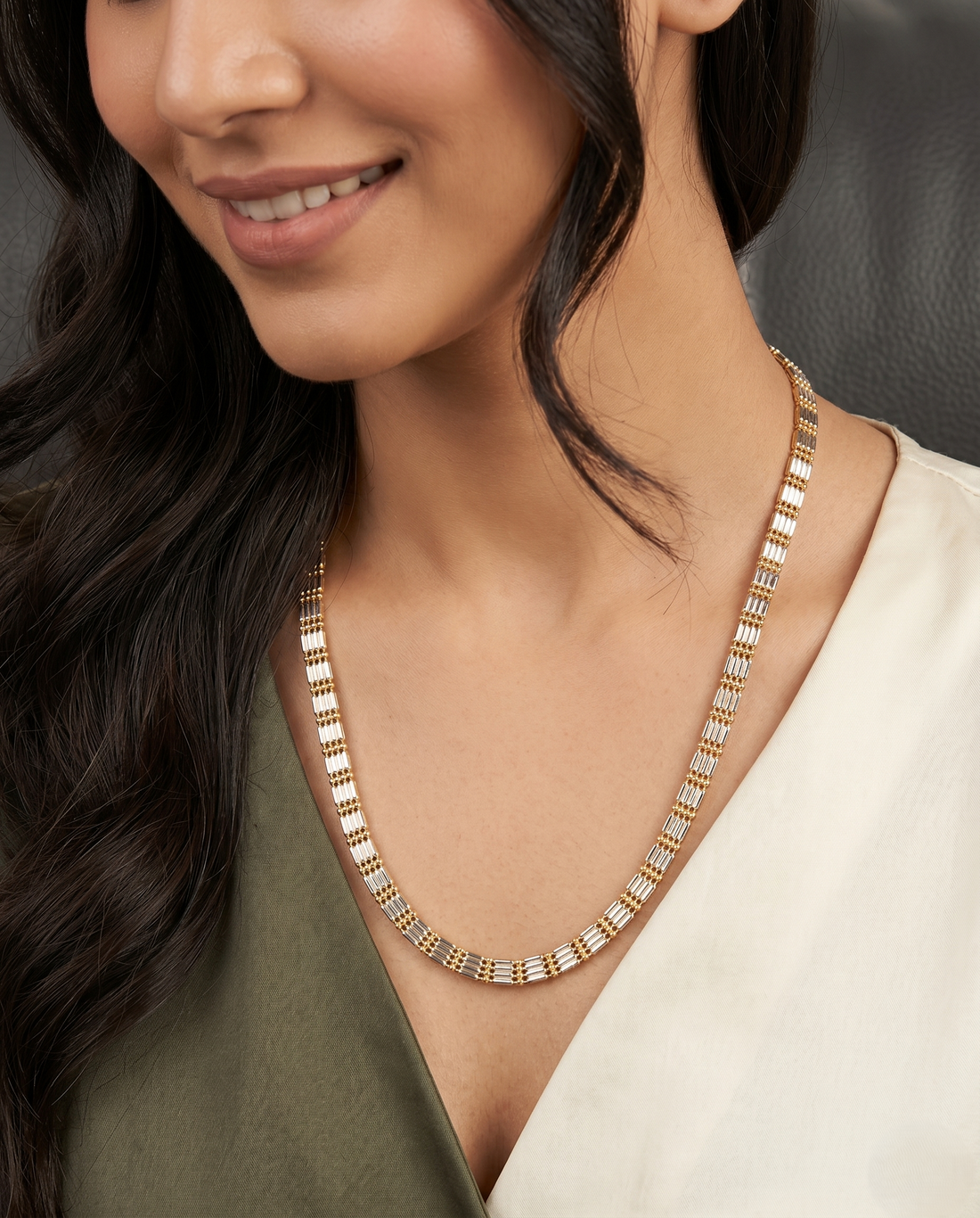 Woman wearing a gold necklace with  neutral background