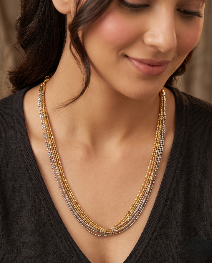Woman wearing a multi-strand beaded necklace with a neutral background