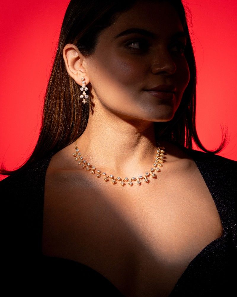 Woman wearing a necklace and earrings against a red background