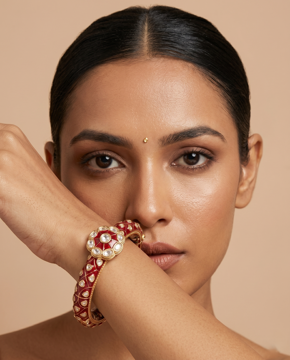 Woman wearing a red and gold bangle on a beige background