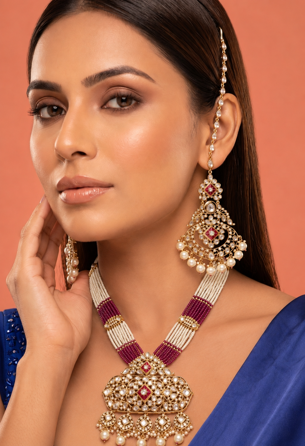 Woman wearing a traditional necklace and earrings against a peach background