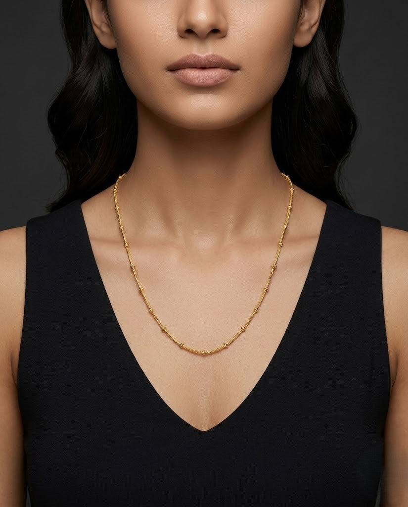 Woman wearing gold necklace against a dark background