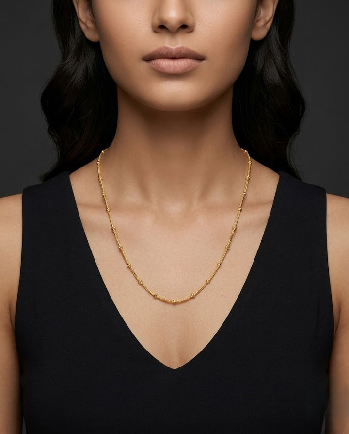 Woman wearing gold necklace against a dark background
