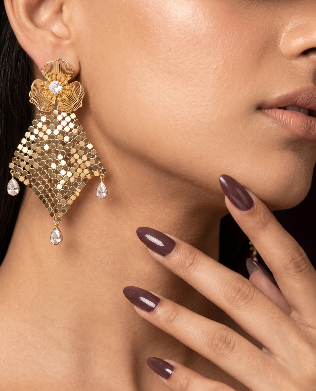 Close-up of a woman wearing gold earrings with a dark background