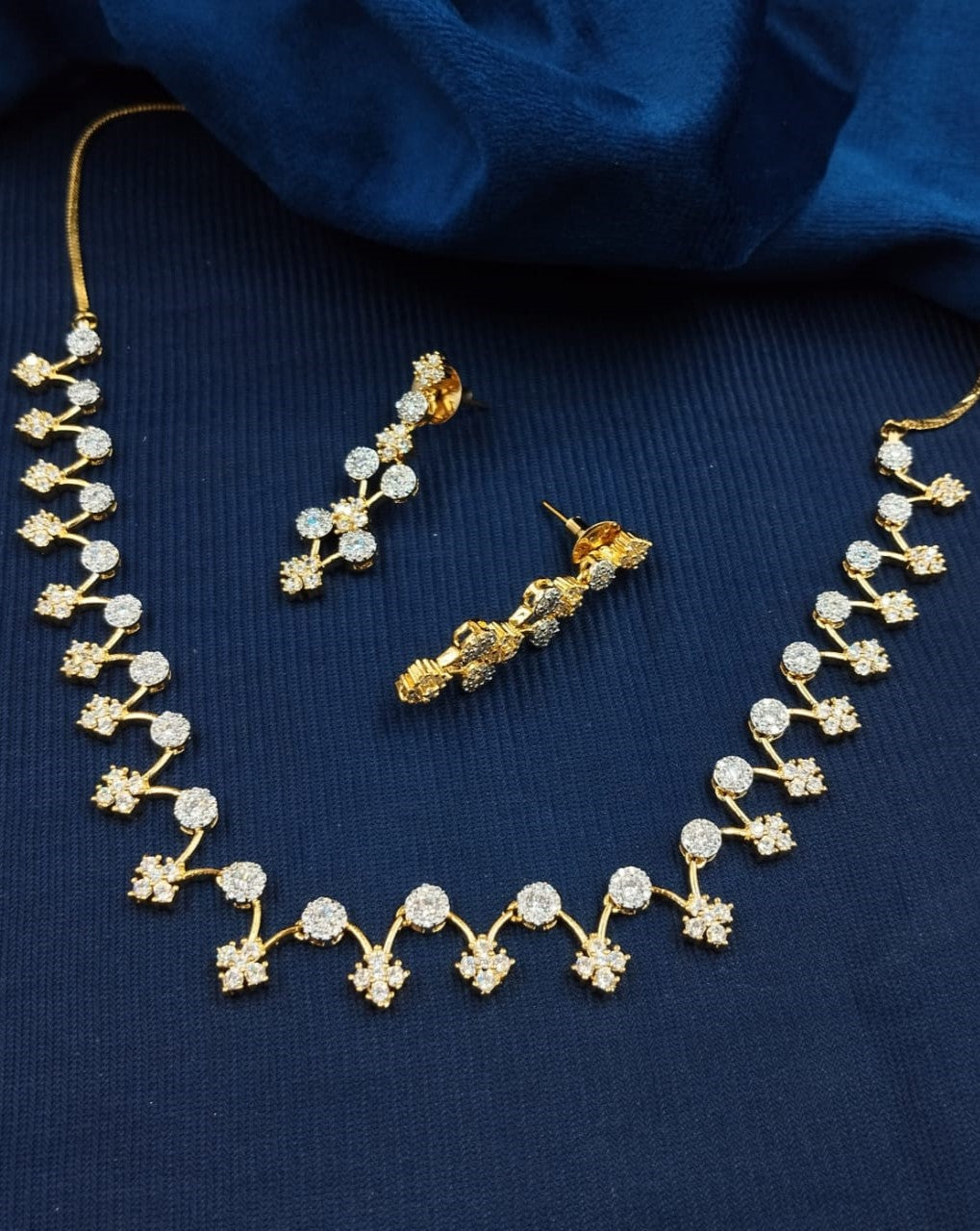 Gold necklace and earrings on a blue fabric background