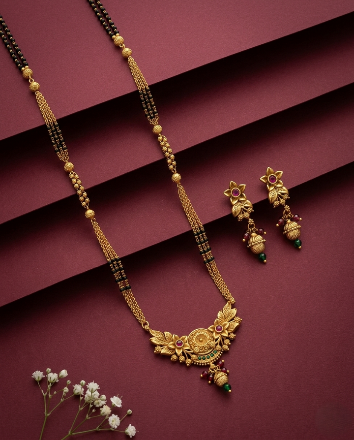 Gold necklace and earrings on a maroon background